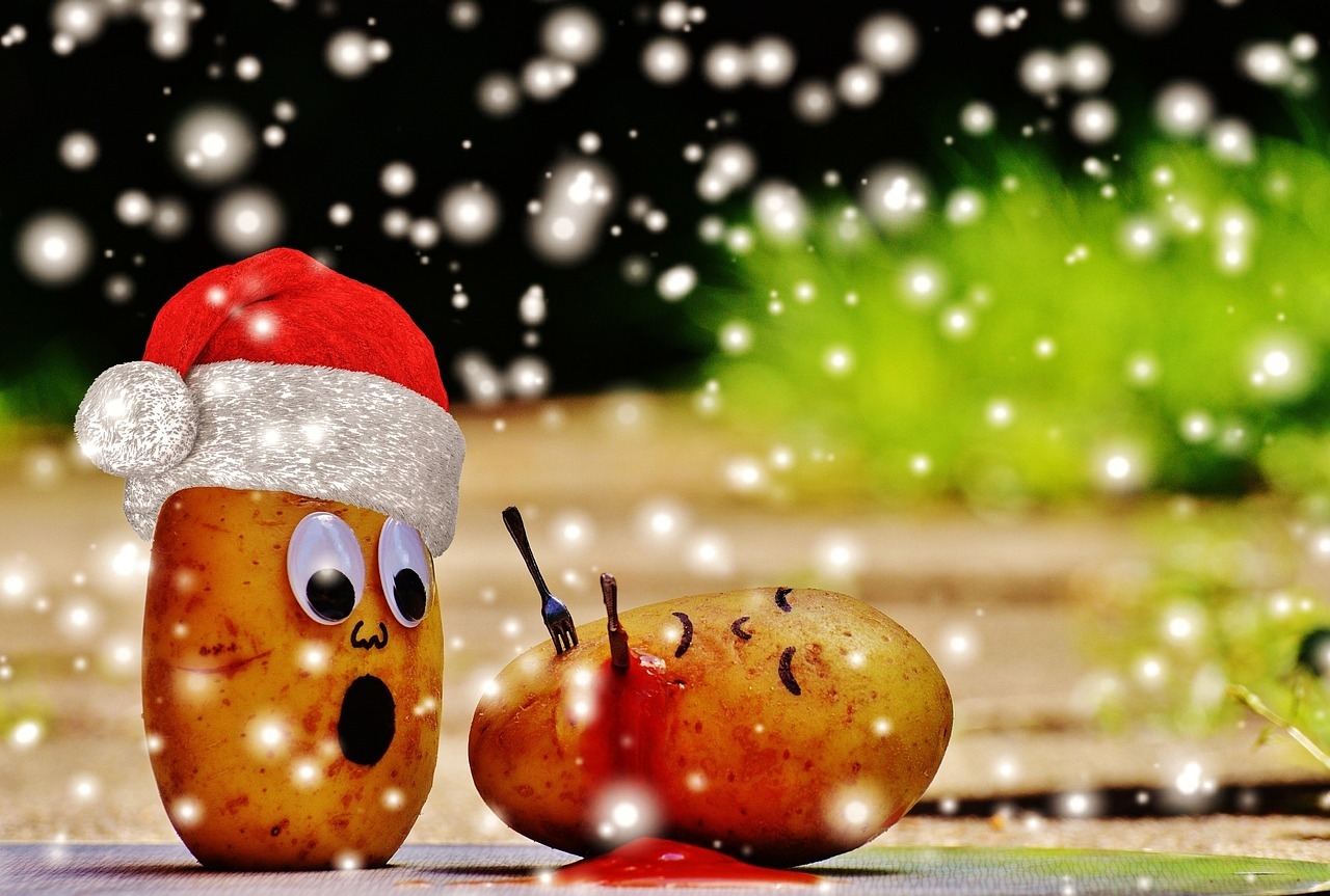 Kampf zweier Kartoffeln mit Weihnachtsmütze und Schneefall
